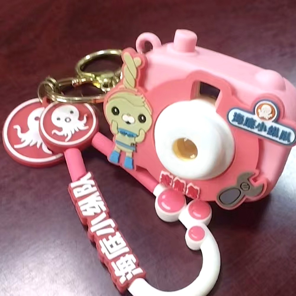 Conjunto personalizado de varias piezas moldeadas: llavero con forma de camara, dije de personaje esculpido, dos placas redondas y correa con letras en relieve
