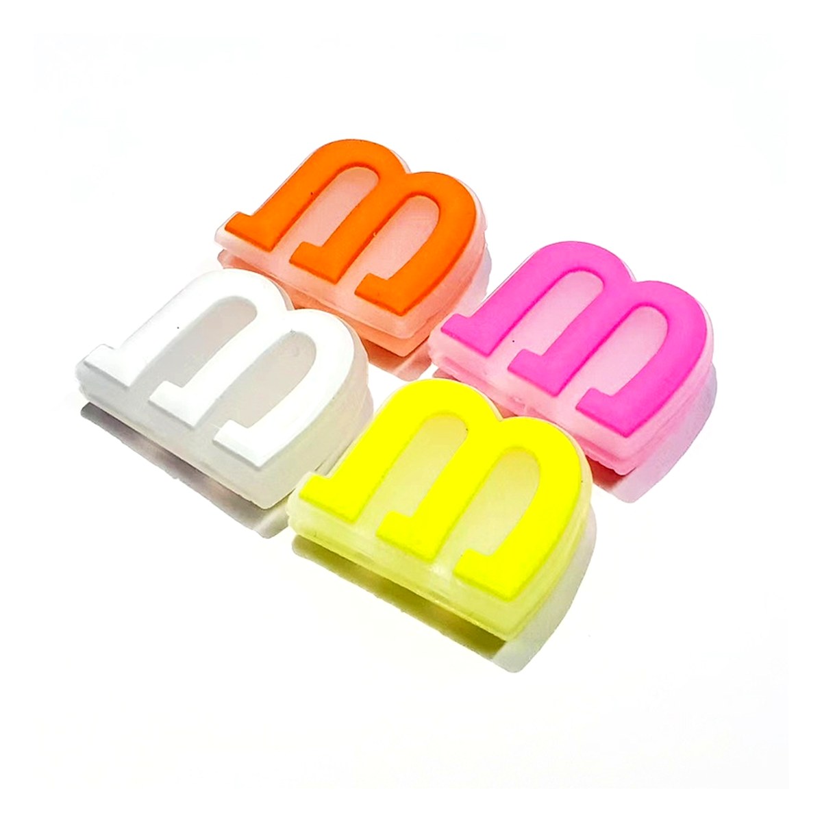 Custom silicone tennis racket shock absorbers moulded as a raised letter shape in four colours