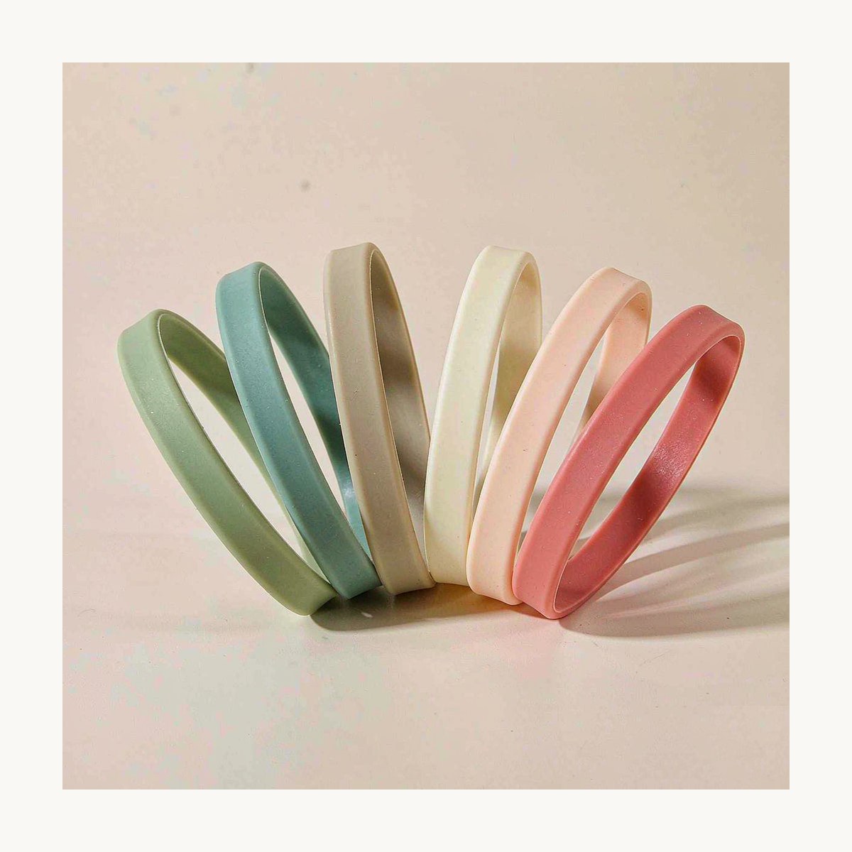Gama de pulseras de silicona personalizadas en colores suaves sobre fondo blanco roto